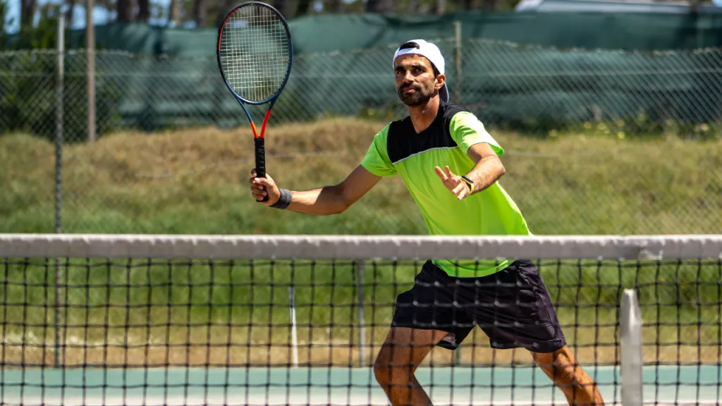 Tennis player positioned at the net ready to hit a drop volley