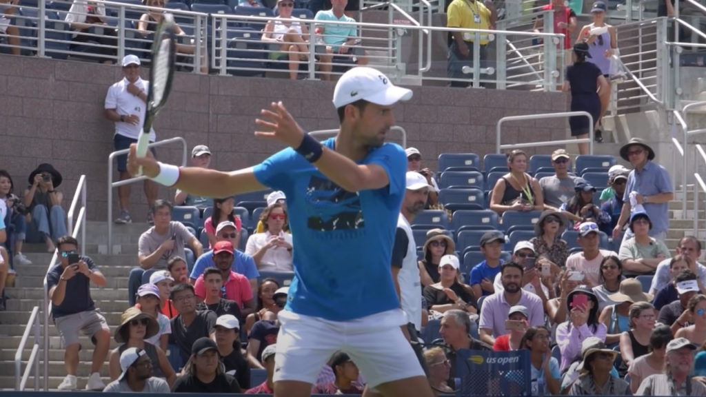 in this picture novak is preparing his forehand stroke where a completing his back swing by bringing his racket all the way back behind him. the racket face is pointing to backfence or wall, his non dominant shoulder is pointing towards the oncoming ball and the non hitting hand is showing to the side fence.